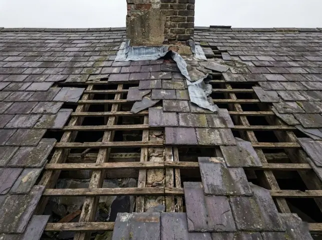 Roof with multiple missing and cracked slate tiles